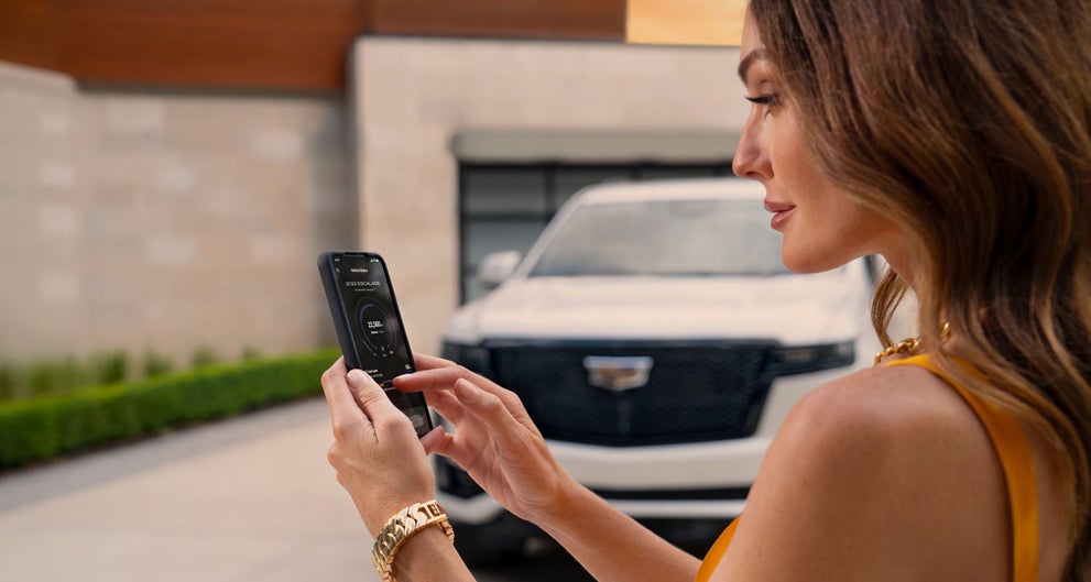 lady checking her mobile with a Cadillac vehicle background | Ed Morse Cadillac Delray Beach FL in Delray Beach FL