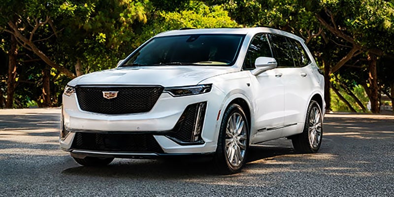 white Cadillac XT6 near forest